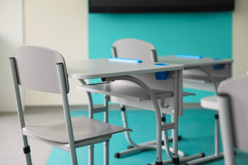 Stylish classroom with desks and chairs at school, closeup