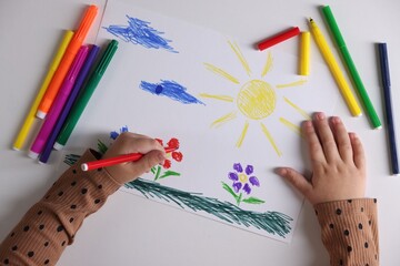Cute little girl drawing with felt pen at white table, top view