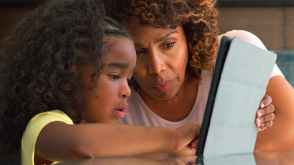 Grandmother Helping Granddaughter To Use Digital Tablet On Table At Home