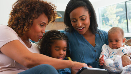 Multi-Generation African American Family With Baby At Home Sitting On Sofa Watching TV Together