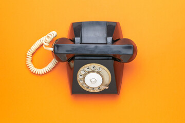 Vintage Black Rotary Telephone on Vibrant Orange Background for Retro Communication Themes