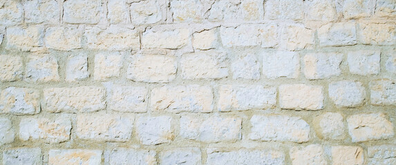 Textured wall made of light colored bricks with visible mortar between bricks