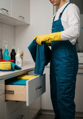 A cleaning company employee wearing rubber gloves lays out cleaning supplies in preparation for cleaning.