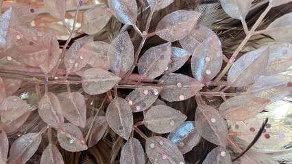 Close-up of sparkling, iridescent blush pink leaves with glitter particles for a soft background