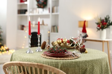 Festive table setting with Christmas decor and burning candles indoors