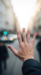 Man with his hand raised in a stop gesture, showing the palm of his hand against a blurry city street background with lights. Road safety and caution concept.
