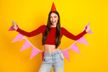 Party loving young woman celebrates birthday with pink polka dot bunting against bright yellow background