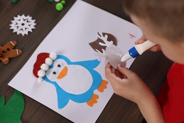 Little boy making Christmas postcard at wooden table, closeup. Child handmade craft © New Africa