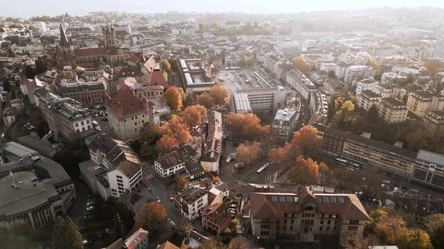 Aerial view of Lausanne Cathedral and cityscape, with buildings and autumn trees casting shadows in golden light, Lausanne, Vaud, Switzerland.