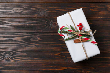 Fototapeta premium Decorated Christmas gift with candy cane on wooden background, top view. Space for text