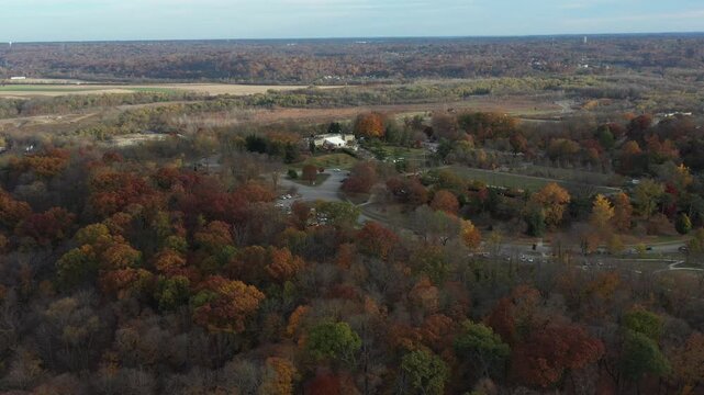 Aerial view of Ault Park surrounded by trees in autumnal hues, showcasing a blend of green lawns and walkways, Cincinnati, Ohio, United States.