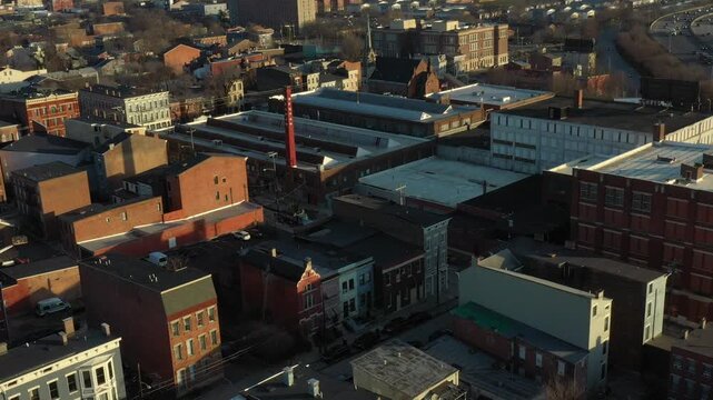 Aerial view of mixed brick buildings and an adjacent highway teeming with cars, the scene bathed in the warm glow of evening, Cincinnati, Ohio, United States.