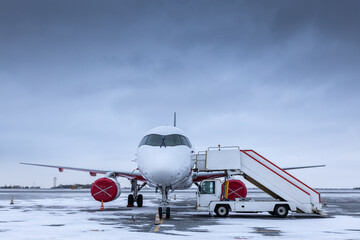 White passenger jet plane with air stairs on the winter airport