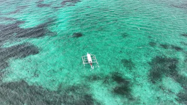 Aerial view of a boat sailing on the clear turquoise water, creating a striking contrast between the vessel and the sea, Siargao, Philippines.