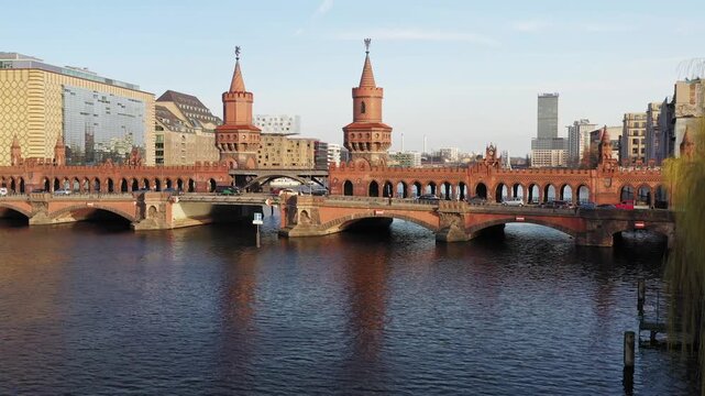 Aerial view of the iconic red-brick Oberbaum Bridge spanning the tranquil Spree river, framed by modern buildings, Berlin, Berlin, Germany.