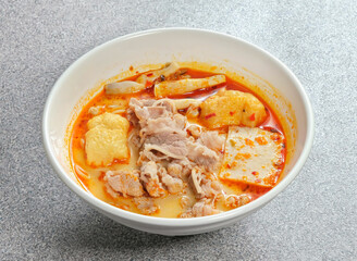 A tantalizing bowl of spicy Asian noodle soup with savory pork, tofu, and mushrooms. A culinary delight, a flavorful journey for the senses. Comfort food!