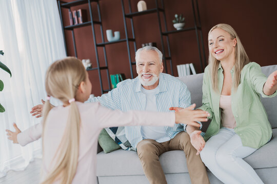 Heartwarming family moment as daughter runs to hug grandpa and mom smiles in cozy home setting