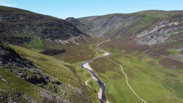 Aerial view of the River South Esk winding through a valley, its waters reflecting the sky amidst the lush green and brown landscape, Brechin, Scotland, United Kingdom.