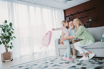 Happy family moment with grandparents and child at home a warm hug and playful goodbye as mom dad and daughter share love in a cozy living room