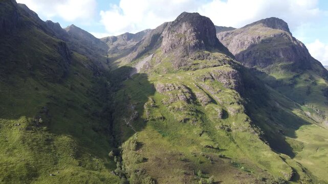 Aerial view of the majestic Three Sisters mountains, with steep slopes and grassy patches creating a textured landscape, Glencoe, Scotland, United Kingdom.