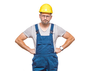 Impatient middle-aged construction worker with hands on waist looking to camera, isolated on white background. Angry repairman. Craftsman against white wall