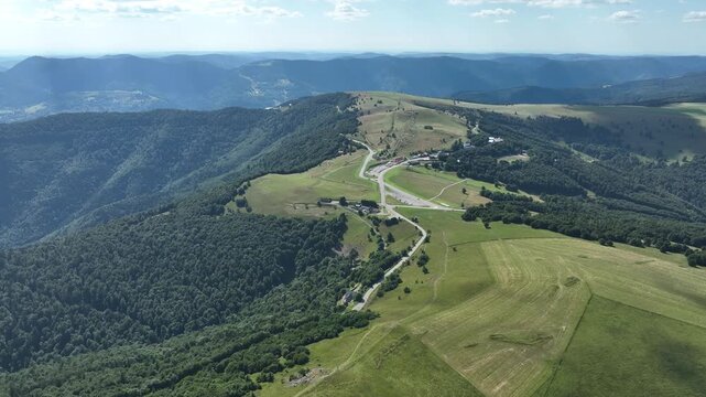 Aerial view of Route des Cretes winding through lush green hills and dense forests, creating a scenic landscape, Fellering, Grand Est, France.