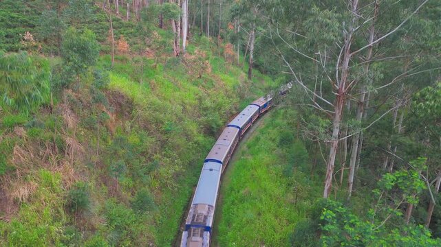 Aerial Crane Up Drone Shot of Train Moving Through Lush Green Mountains