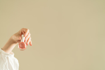 woman's hand holding pink nail polish.