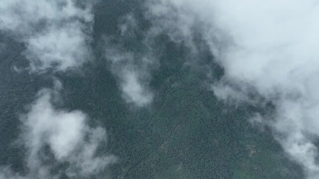 Aerial view of a landscape shrouded in thick, swirling clouds, creating an ethereal and moody atmosphere along Route des Cretes, Fellering, Grand Est, France.