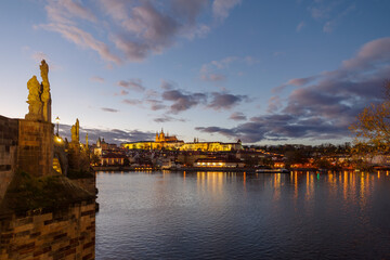 Castle of Prague and Charles bridge reflected on Vltava river at sunset