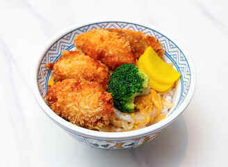 Savor the taste of Japan with a hearty katsudon bowl, featuring crispy fried pork cutlets and vibrant broccoli served over fluffy rice. Enjoy this delight!