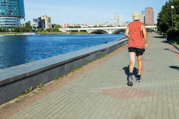 A man runs on a sidewalk near a body of water