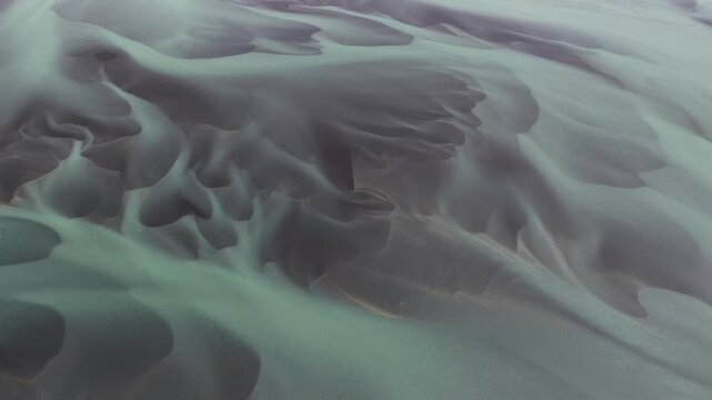 Aerial view of the stunning braided river patterns creating abstract shapes with contrasting colors of grey and light green, Iceland, Iceland.