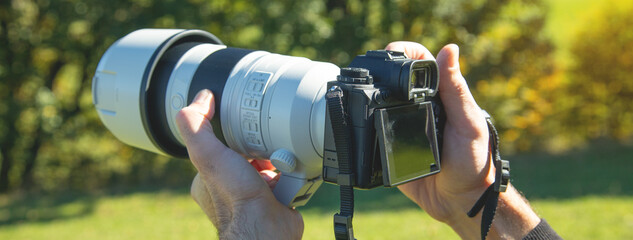 Photographer holding a digital camera taking pictures in nature.