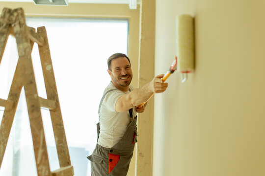 Man painting a wall in a modern interior space during daylight
