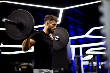 Male athlete lifts barbell in modern gym during a strength training session