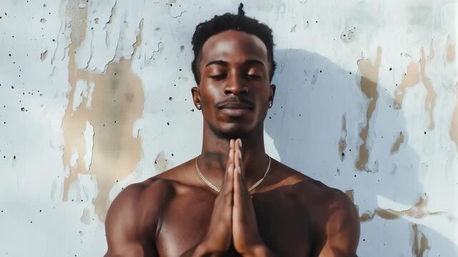 A muscular man in a meditative pose against a wall with peeling plaster symbolises the harmony of strength and spirit, providing a suitable backdrop for motivational posts or fitness projects.
