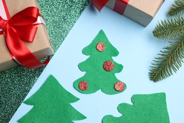 Christmas gifts, handicraft materials and fir branch on light blue background, flat lay. Child handmade craft