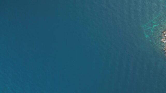 Aerial view of a small, rugged, rocky islet surrounded by the deep blue sea with hints of turquoise near the shoreline, Biograd na Moru, Zadar County, Croatia.