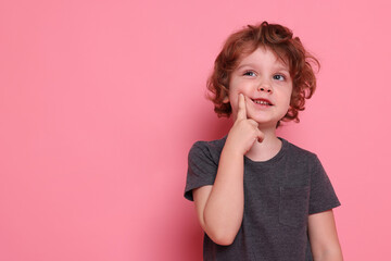 Portrait of cute little boy on pink background, space for text