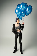 Stylish young woman holds blue balloons in a modern, fashionable setting