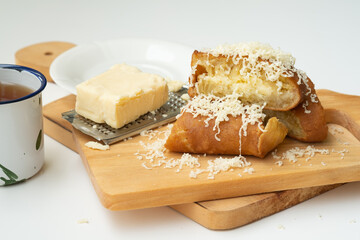 A sweet slice of Martabak Manis (Terang Bulan) topped with grated cheddar cheese and butter on a wooden board; a popular Indonesian street food snack