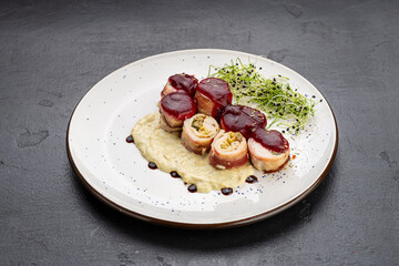 Chicken bacon roulade with berry sauce and creamy puree, plated with microgreens