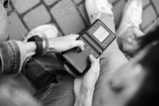 Young people engaged with a handheld device outdoors in a park setting