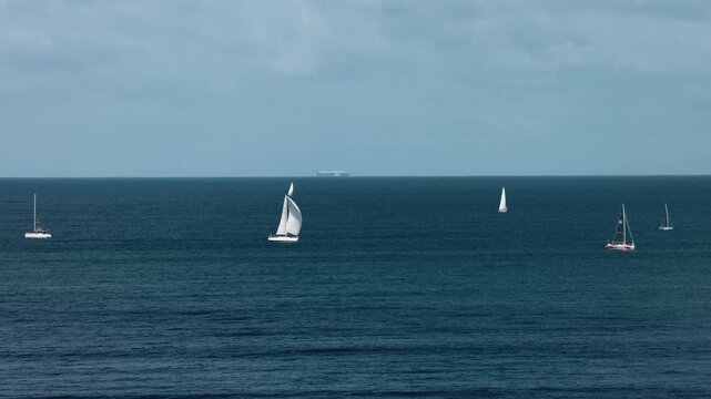Sailboats in the ocean depths, gliding smoothly across the water. The concept of the unity of nature and the freedom of the open sea.