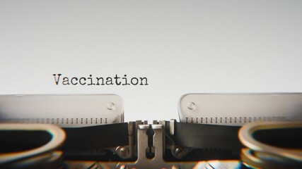 Old mechanical typewriter typing Vaccination Drive in a close-up view, with metal letters striking the white paper.