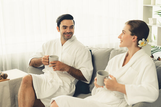 Beauty or body treatment spa salon vacation lifestyle concept with couple wearing bathrobe relaxing with drinks in luxurious hotel spa or resort room. Vacation and leisure relaxation. Quiescent - Powered by Adobe