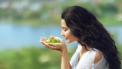 Close-Up of Woman Smelling Organic Tea Leaves with Flower in Hands