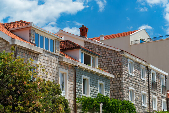 Old European architecture, a view of the facades of buildings in a resort town with stone walls and tiled roofs on a bright sunny day against a blue sky