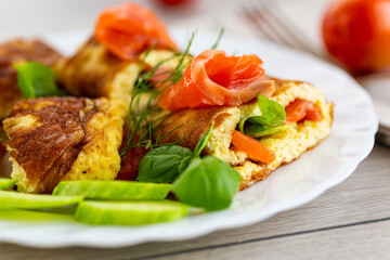 Juicy omelet with salmon pieces and aromatic herbs
